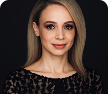 Person wearing a black patterned top against a dark background.